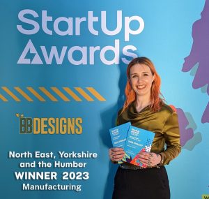 A woman proudly showing her award for StartUp Awards North East, Yorkshire and the Humber Winner 2023.