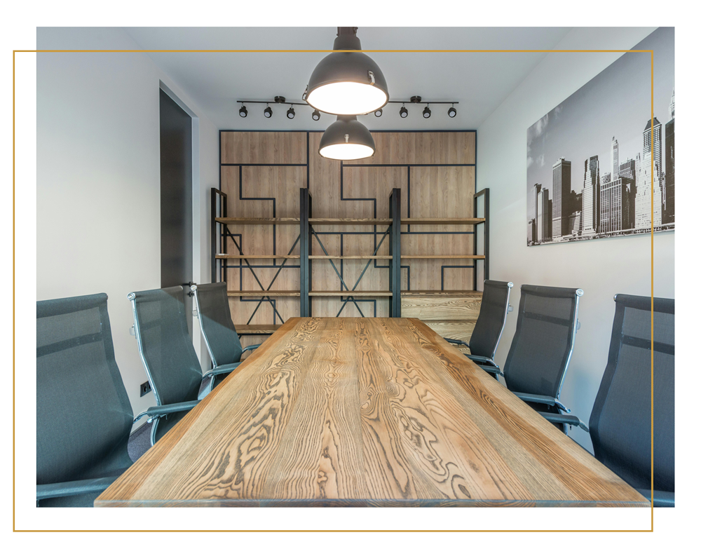 A modern office meeting room with a large wooden table in the centre in a yellow border.