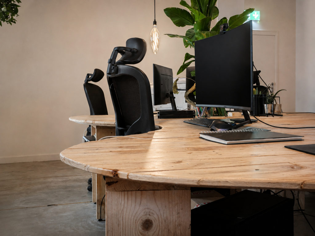 Bespoke curved office desks made from reclaimed timber in a planted commercial workspace with ergonomic seating.